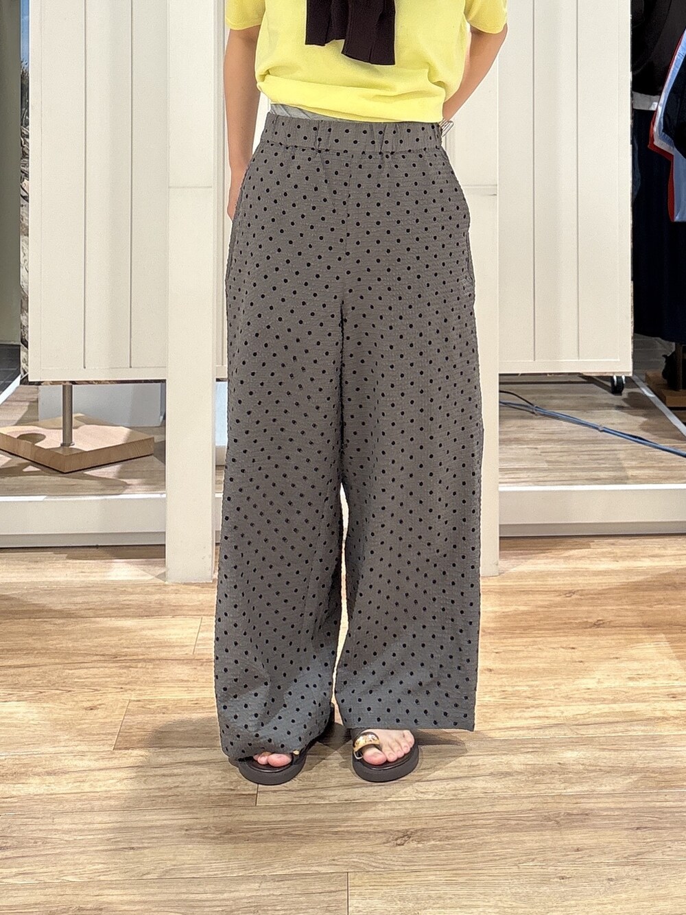 イエロー系のニット/セーター、グレー系のその他パンツ、ブラウン系のサンダルを着用したレディースの夏コーディネートの8枚目の写真