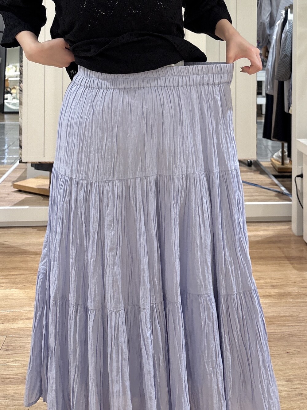 ブルー系のスカート、ブラック系のパンプス、シルバー系のトートバッグを着用したレディースの春コーディネートの6枚目の写真