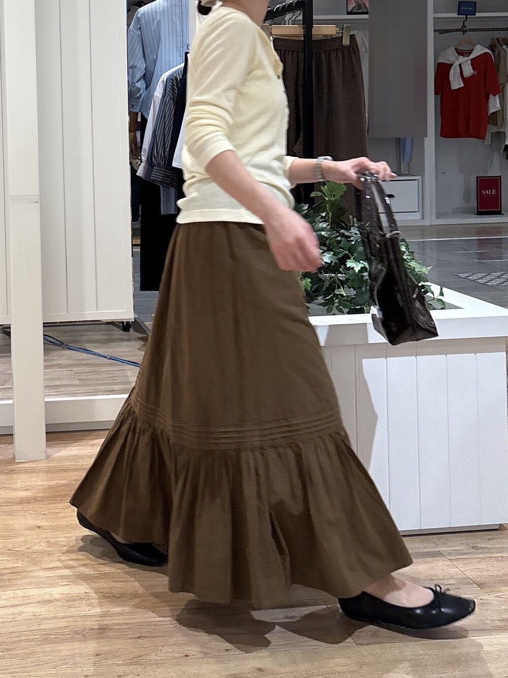 イエロー系のTシャツ/カットソー、ブラウン系のスカート、ブラック系のパンプスを着用したレディースの秋コーディネートの4枚目の写真