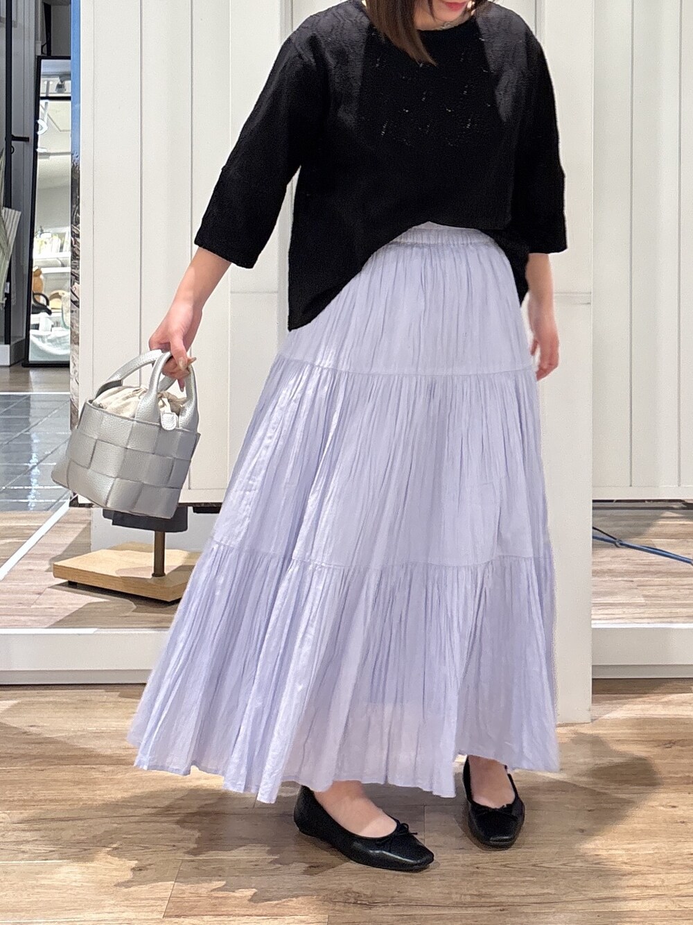 ブルー系のスカート、ブラック系のパンプス、シルバー系のトートバッグを着用したレディースの春コーディネートの4枚目の写真