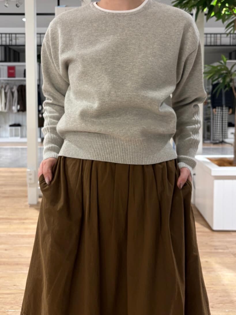 グレー系のニット/セーター、ブラウン系のスカート、ブラック系のブーツを着用したレディースの冬コーディネートの6枚目の写真