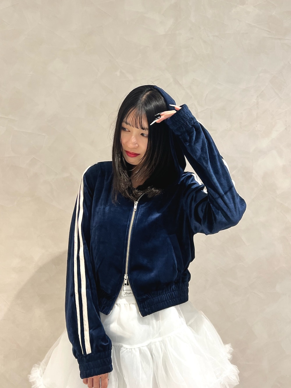 ブルー系のパーカー、ホワイト系のスカート、ブラック系のブーツを着用したレディースの秋コーディネートの4枚目の写真