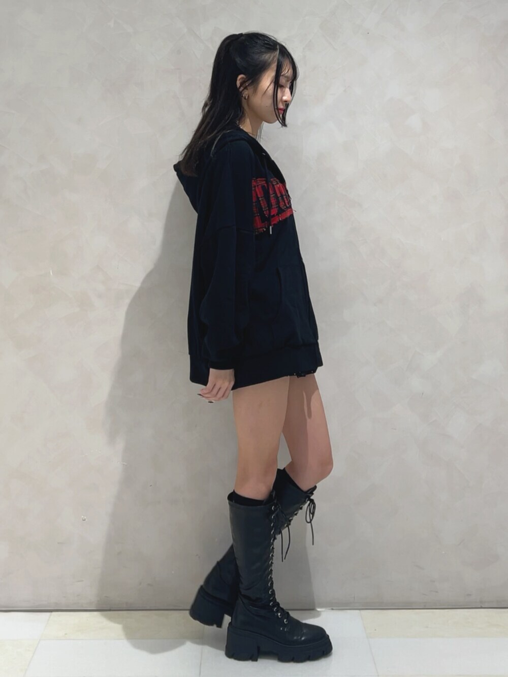 ブラック系のブーツ、ブラック系のパーカー、ブラック系のスカートを着用したレディースの秋コーディネートの2枚目の写真