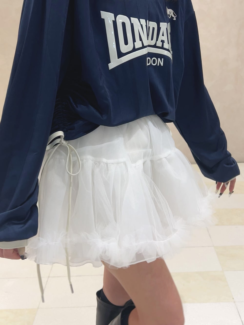 ブルー系のTシャツ/カットソー、ホワイト系のスカート、ブラック系のブーツを着用したレディースの秋コーディネートの6枚目の写真