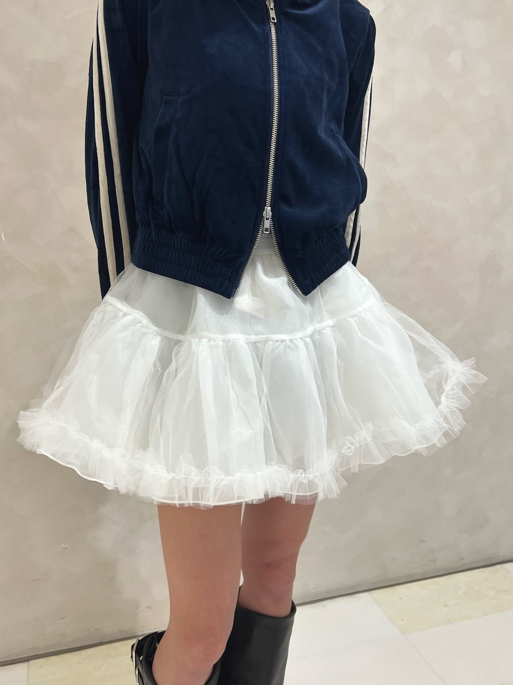 ブルー系のパーカー、ホワイト系のスカート、ブラック系のブーツを着用したレディースの秋コーディネートの6枚目の写真