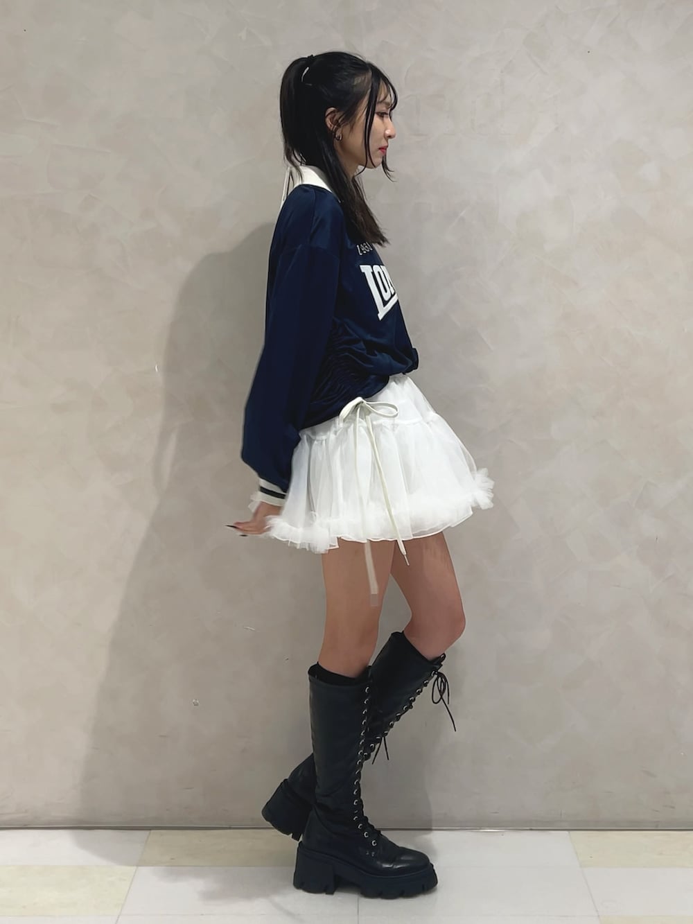 ブルー系のTシャツ/カットソー、ホワイト系のスカート、ブラック系のブーツを着用したレディースの秋コーディネートの2枚目の写真