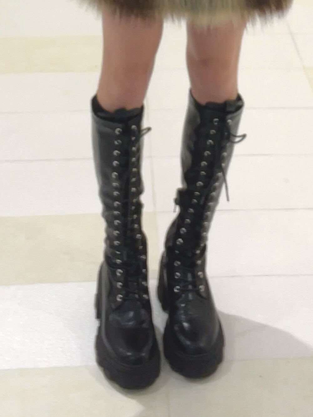 ブラック系のニット/セーター、ブルー系のスカート、ブラック系のブーツを着用したレディースの秋コーディネートの6枚目の写真