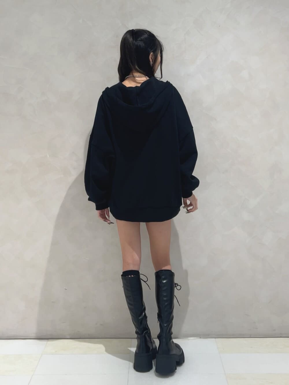 ブラック系のブーツ、ブラック系のパーカー、ブラック系のスカートを着用したレディースの秋コーディネートの3枚目の写真