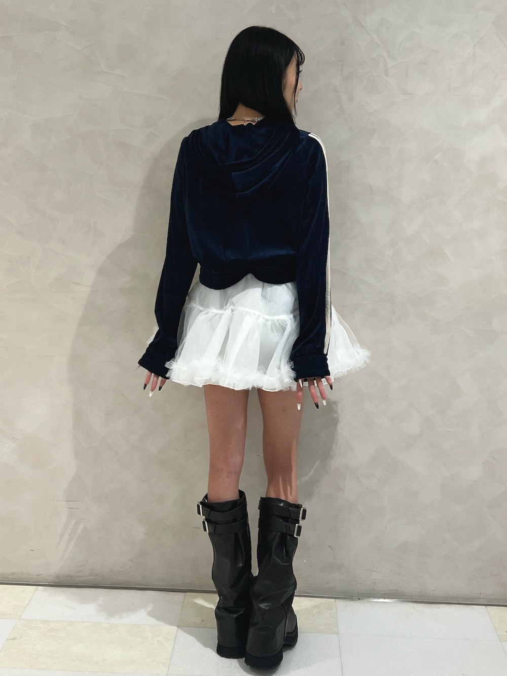 ブルー系のパーカー、ホワイト系のスカート、ブラック系のブーツを着用したレディースの秋コーディネートの3枚目の写真