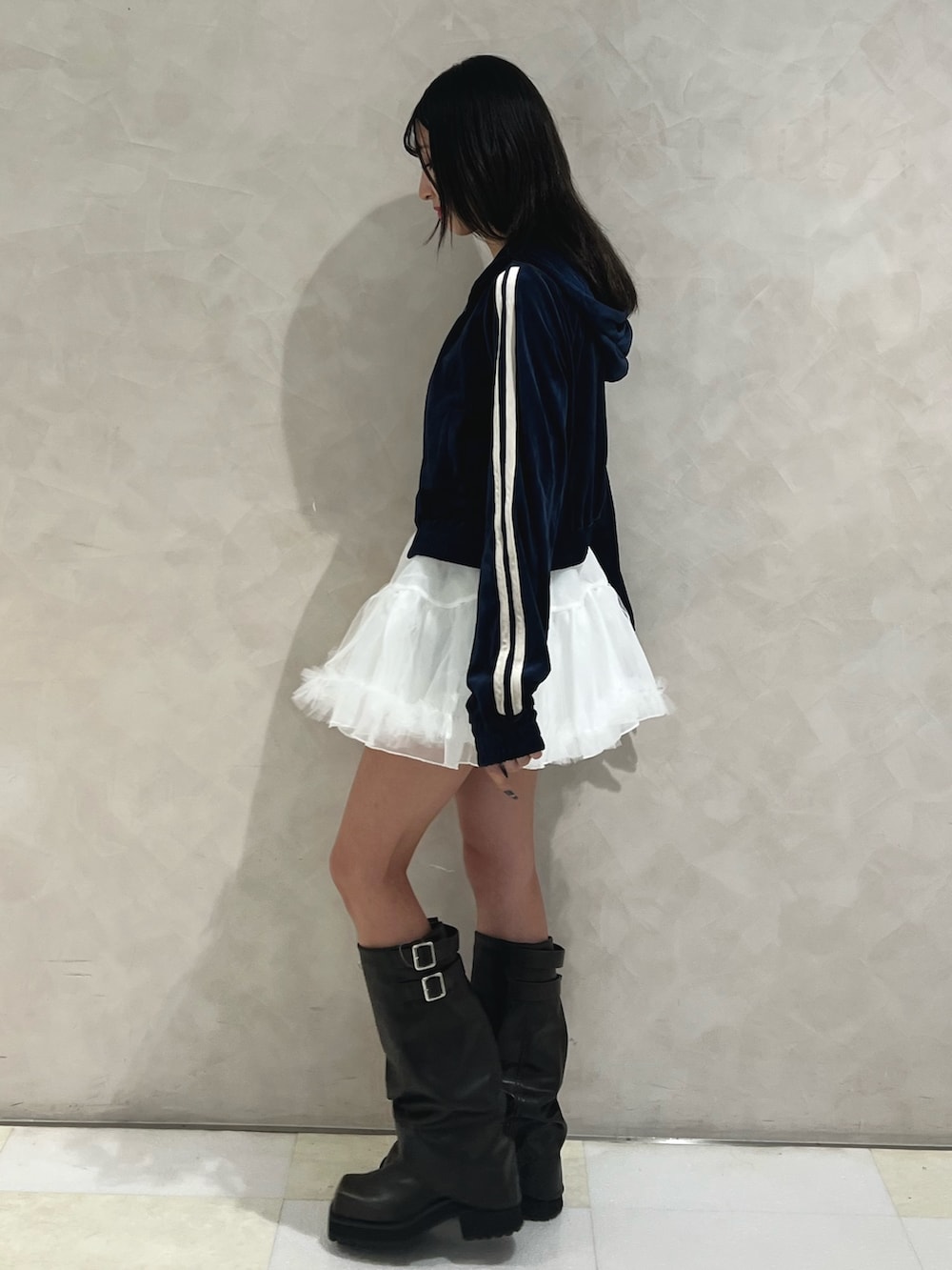 ブルー系のパーカー、ホワイト系のスカート、ブラック系のブーツを着用したレディースの秋コーディネートの2枚目の写真