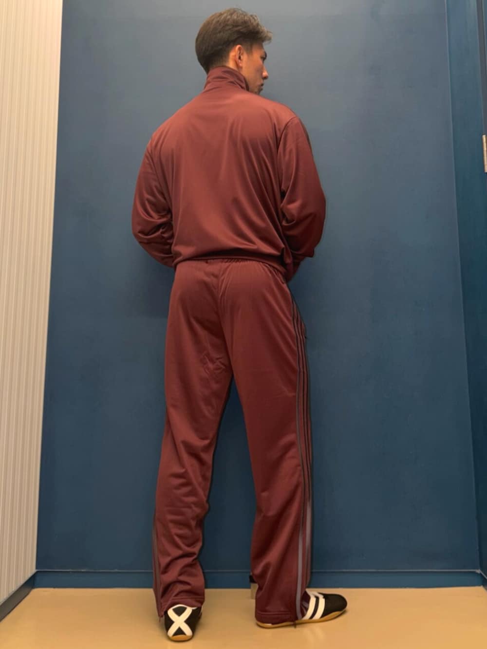 レッド系のトップス、レッド系のパンツ、ブラック系のスニーカーを着用したメンズの春コーディネートの2枚目の写真