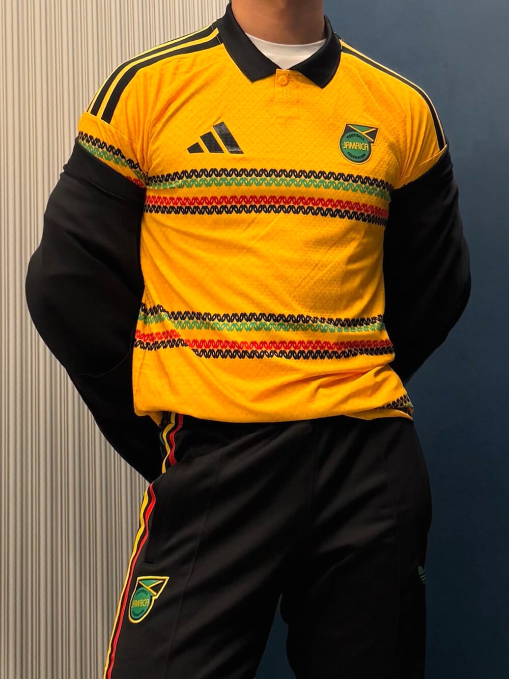 グリーン系のトップス、ブラック系のジャージ、ブラック系のスウェットパンツを着用したメンズの春コーディネートの2枚目の写真