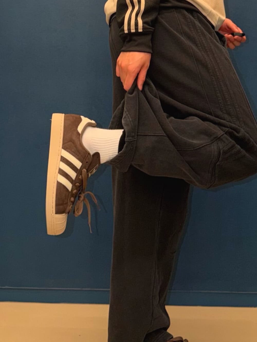 ブラック系のパンツ、ベージュ系のジャージ、ブラウン系のスニーカーを着用したメンズの春コーディネートの2枚目の写真