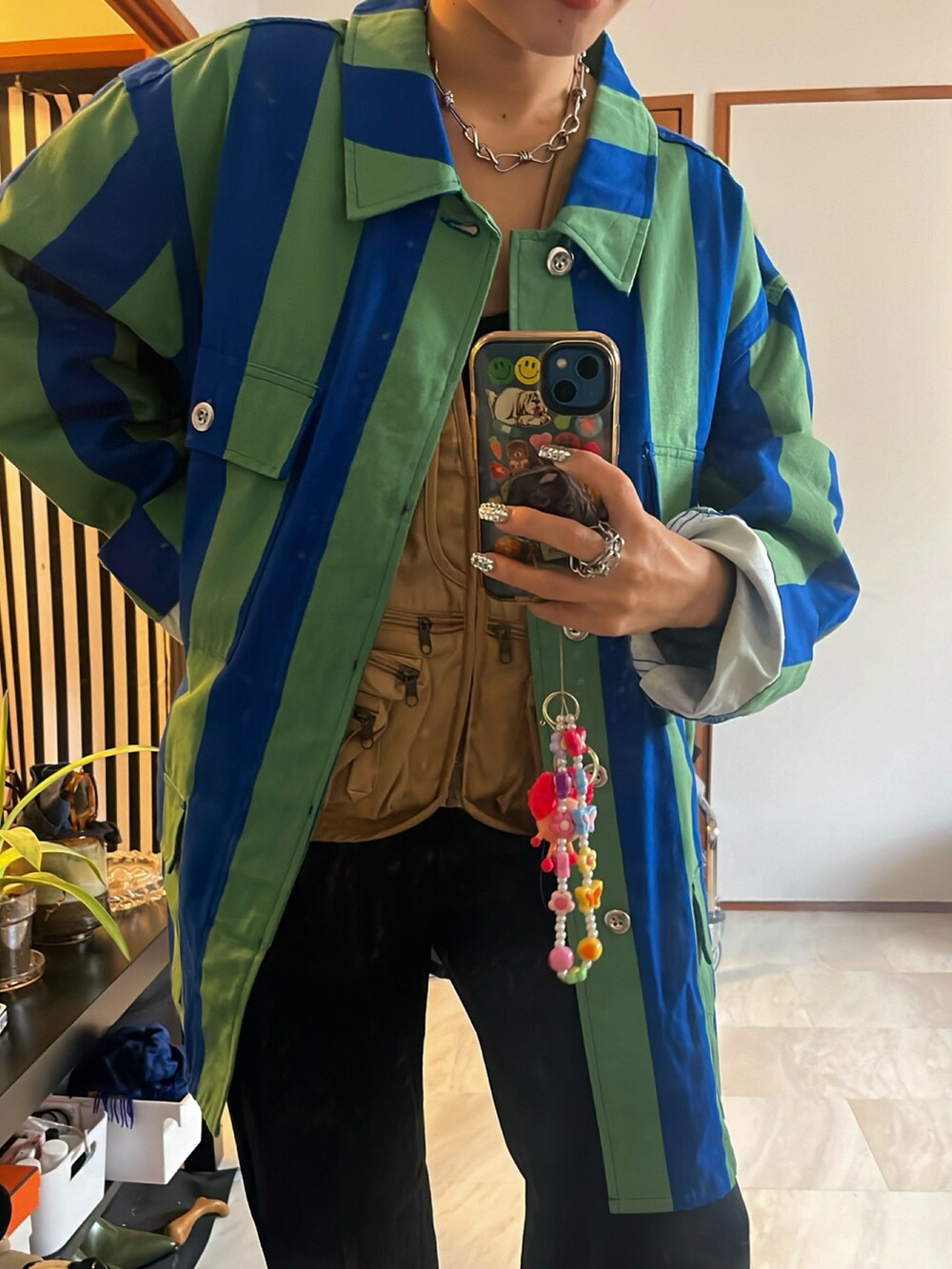 ベージュ系のベスト、グリーン系のシャツ/ブラウス、ブラック系のスラックスを着用したレディースの秋コーディネートの2枚目の写真