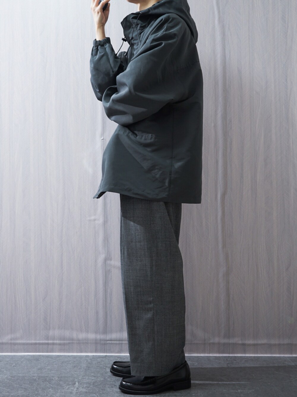 グレー系のスラックス、ブラック系のローファー、グレー系のマウンテンパーカーを着用したメンズの冬コーディネートの2枚目の写真