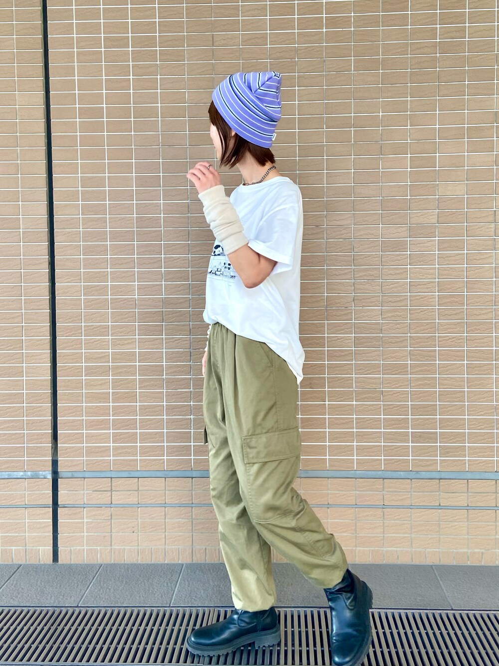 ホワイト系のTシャツ/カットソー、グリーン系のカーゴパンツ、ブラック系のブーツを着用したレディースの秋コーディネートの2枚目の写真