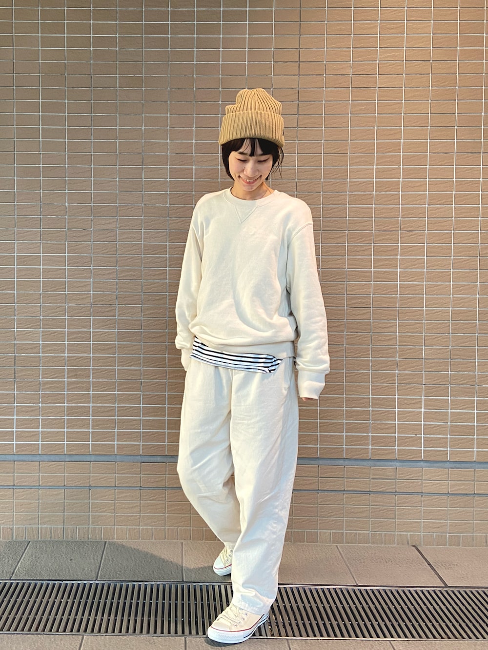 ホワイト系のスニーカー、ベージュ系のニットキャップ/ビーニーを着用したレディースの冬コーディネートの2枚目の写真