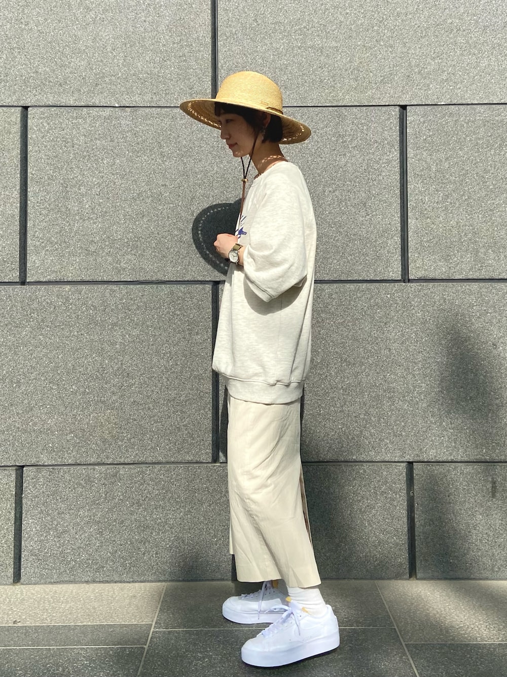 ベージュ系のTシャツ/カットソー、ベージュ系のスカート、ホワイト系のスニーカーを着用したレディースの春コーディネートの2枚目の写真