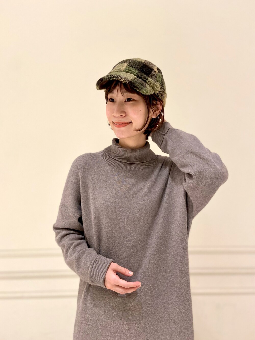 ブラウン系のワンピース、ホワイト系のスニーカー、グリーン系のキャップを着用したレディースの秋コーディネートの2枚目の写真