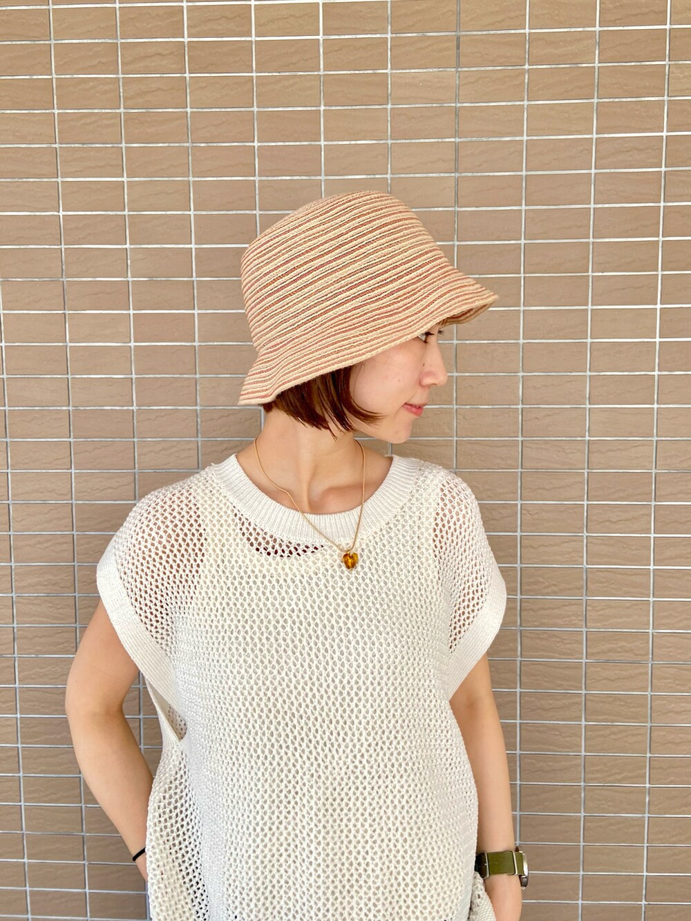 ホワイト系のタンクトップ、ベージュ系のサンダル、ベージュ系のハットを着用したレディースの夏コーディネートの3枚目の写真