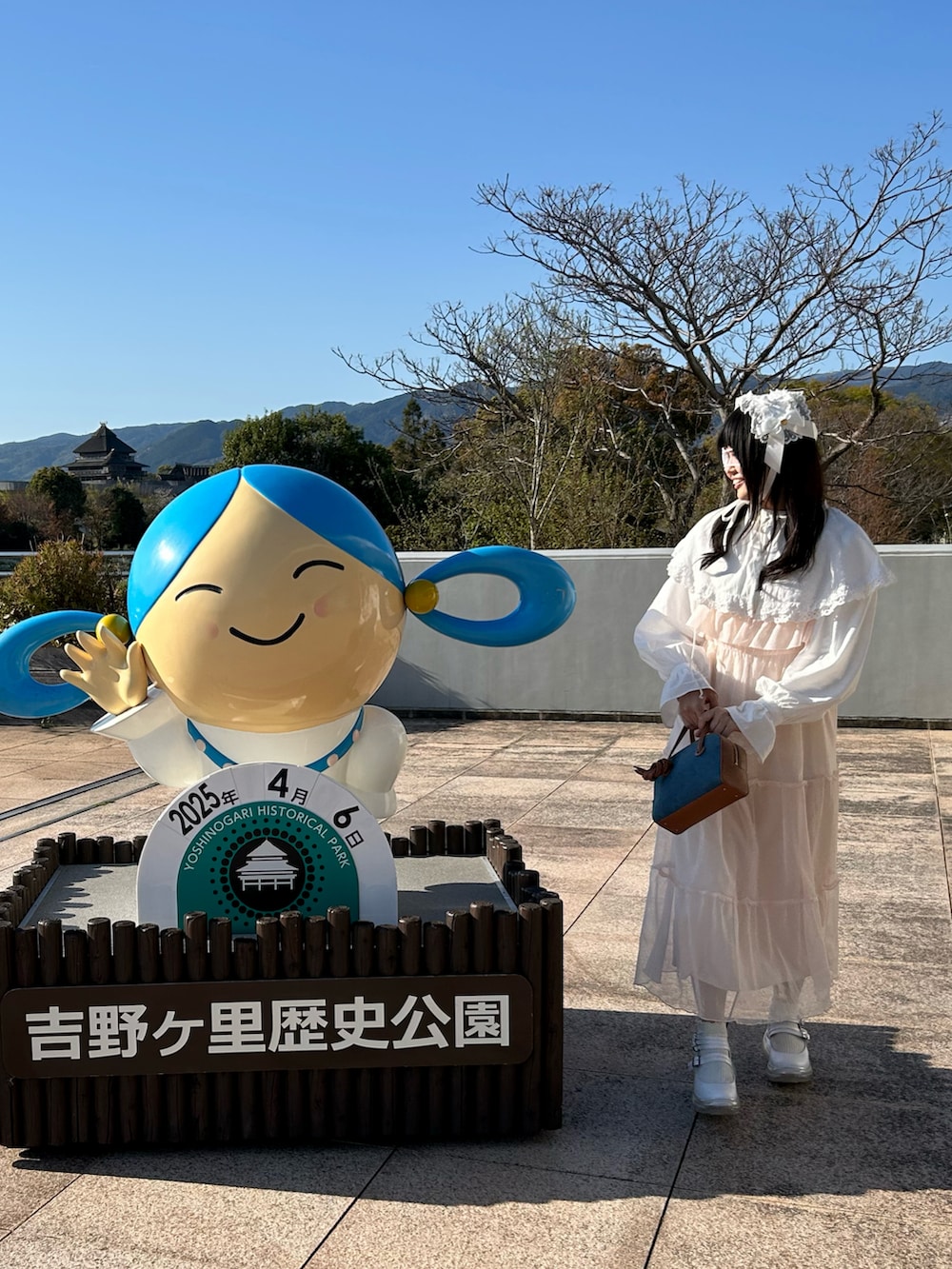 ホワイト系のバレエシューズ、ブルー系のハンドバッグ、ピンク系のワンピースを着用したレディースの春コーディネートの2枚目の写真