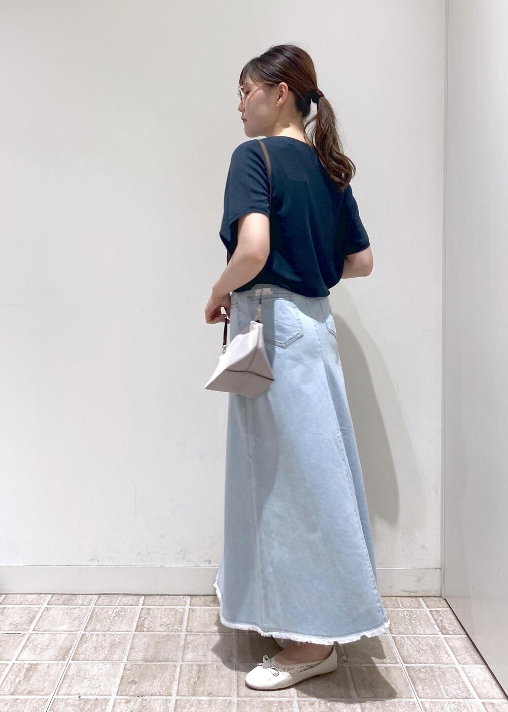 グレー系のショルダーバッグ、ブルー系のデニムスカート、グリーン系のニット/セーターを着用したレディースの夏コーディネートの3枚目の写真