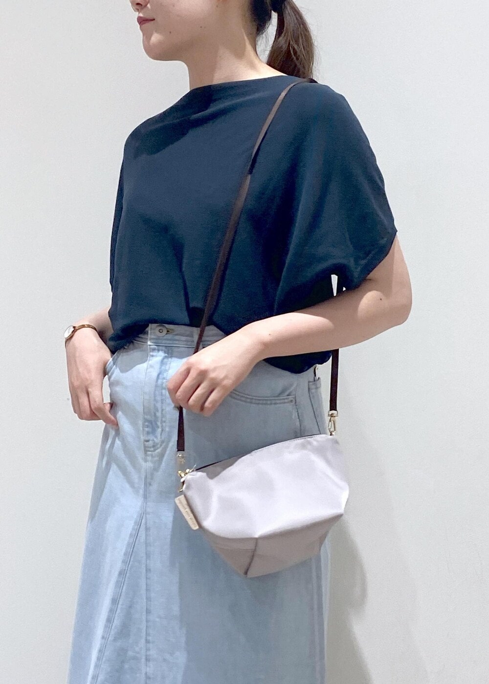 グレー系のショルダーバッグ、ブルー系のデニムスカート、グリーン系のニット/セーターを着用したレディースの夏コーディネートの8枚目の写真