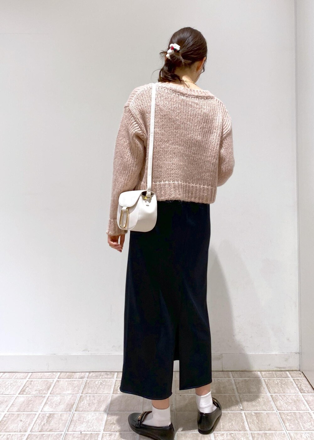 ブラック系のスカート、ベージュ系のムートンコート、ホワイト系のショルダーバッグを着用したレディースの冬コーディネートの4枚目の写真