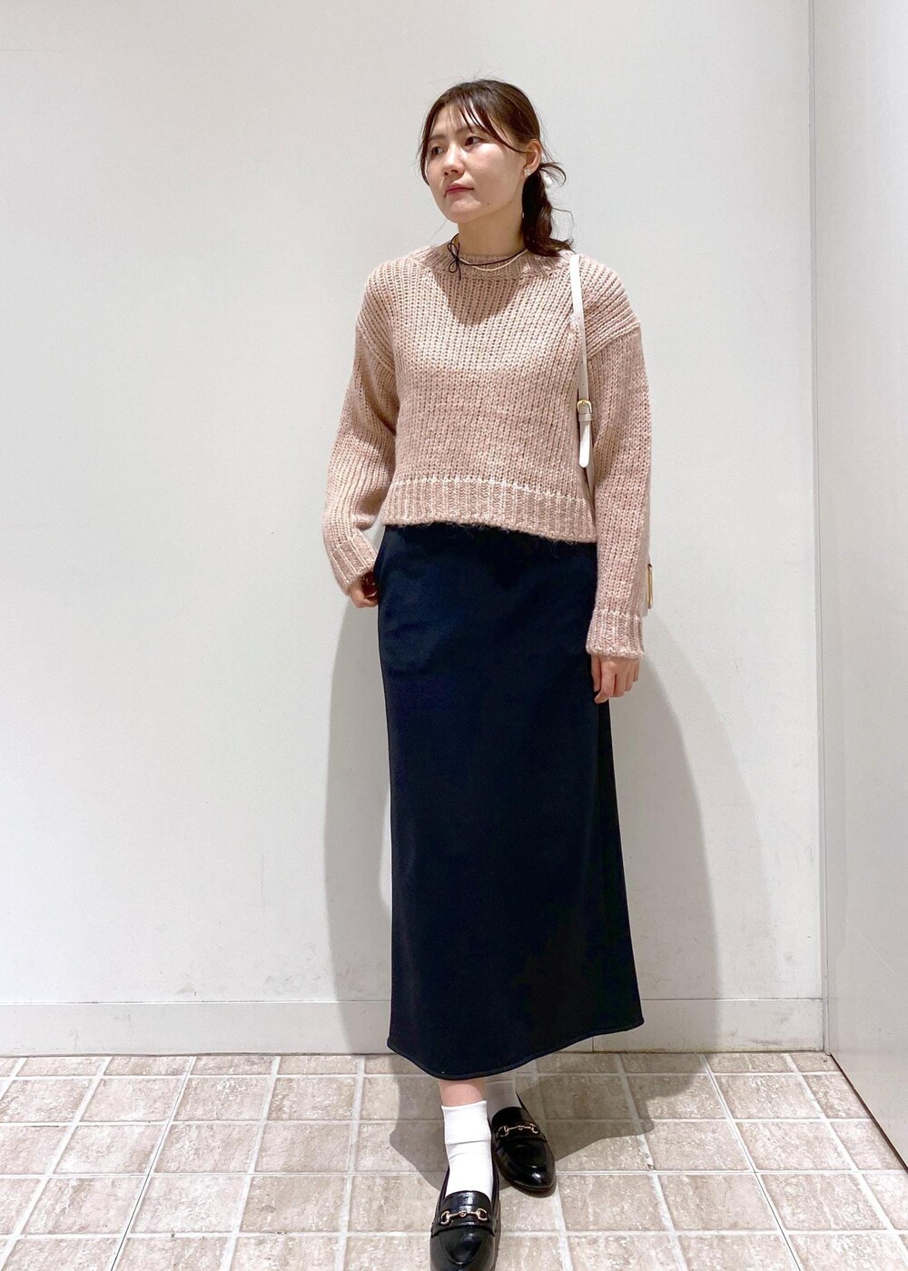 ブラック系のスカート、ベージュ系のムートンコート、ホワイト系のショルダーバッグを着用したレディースの冬コーディネートの3枚目の写真