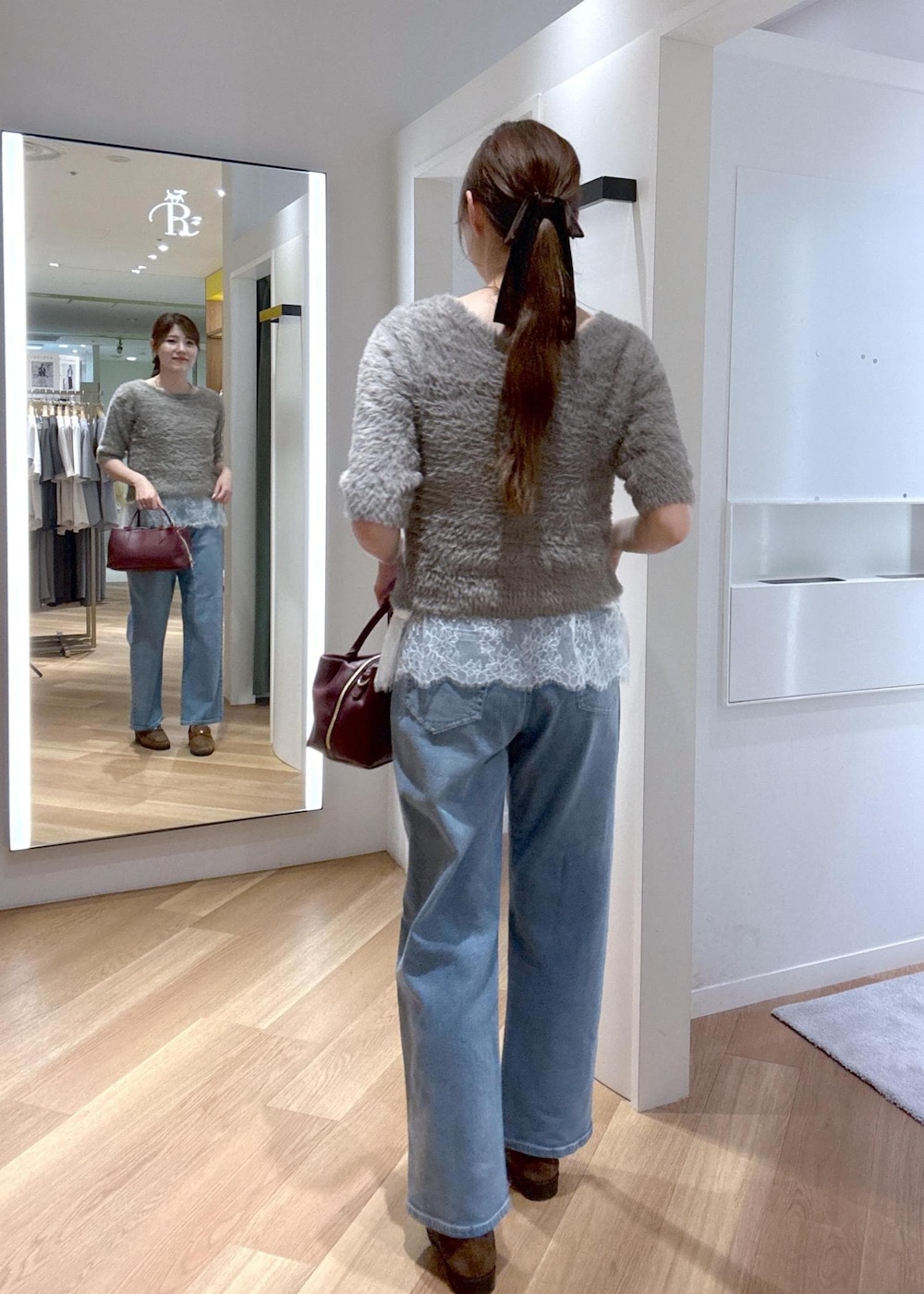ブルー系のデニムパンツ、ホワイト系のキャミソール、レッド系のトートバッグを着用したレディースの秋コーディネートの2枚目の写真