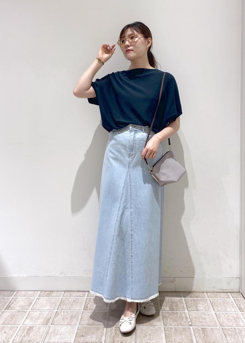 グレー系のショルダーバッグ、ブルー系のデニムスカート、グリーン系のニット/セーターを着用したレディースの夏コーディネートの2枚目の写真