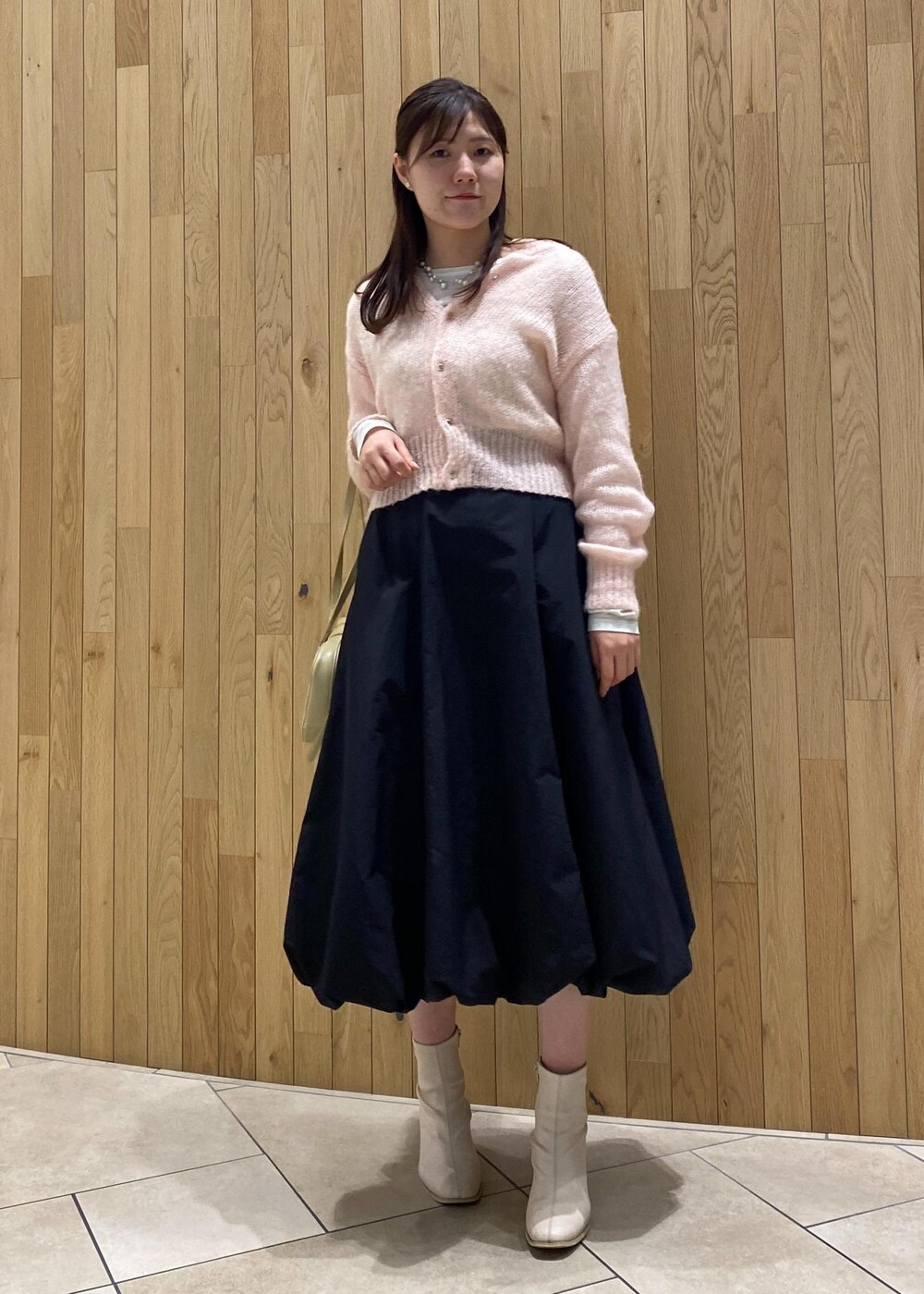 ピンク系のカーディガン/ボレロ、ブラック系のスカート、ベージュ系のボストンバッグを着用したレディースの秋コーディネートの3枚目の写真