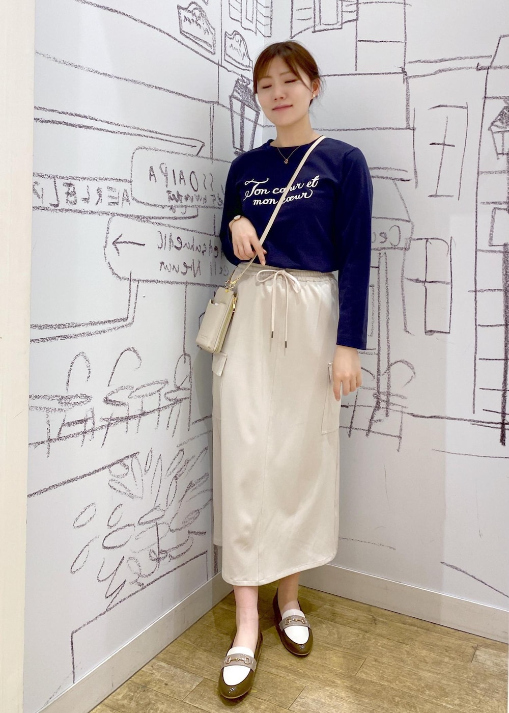 ホワイト系のショルダーバッグ、ベージュ系のスカート、ブラウン系のローファーを着用したレディースの冬コーディネートの2枚目の写真