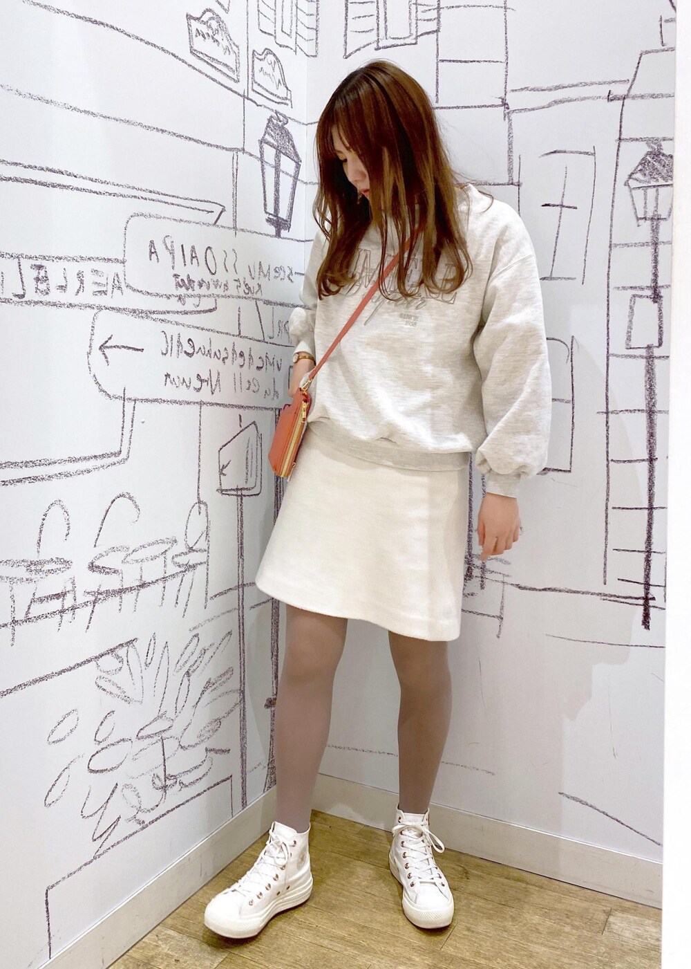 オレンジ系のショルダーバッグ、グレー系のスウェット、ホワイト系のスカートを着用したレディースの冬コーディネートの3枚目の写真
