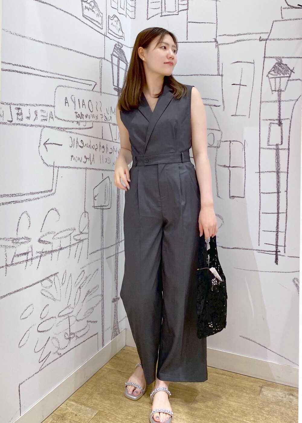 シルバー系のサンダル、ブラック系のトートバッグ、グレー系のつなぎ/オールインワンを着用したレディースの夏コーディネートの2枚目の写真