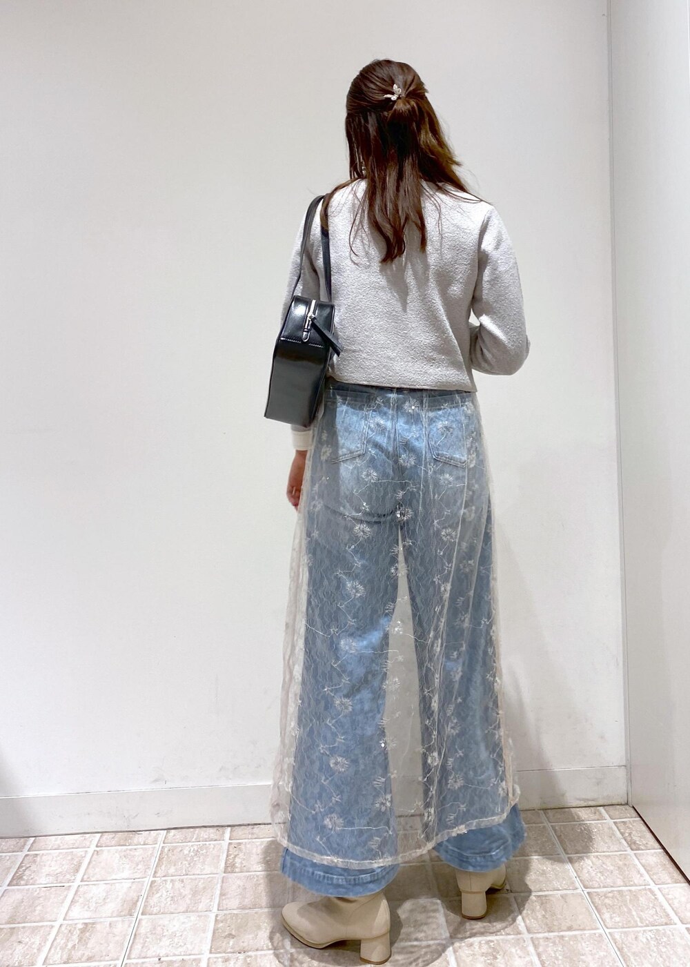 ブルー系のデニムパンツ、グレー系のカーディガン/ボレロ、ホワイト系のスカートを着用したレディースの秋コーディネートの4枚目の写真