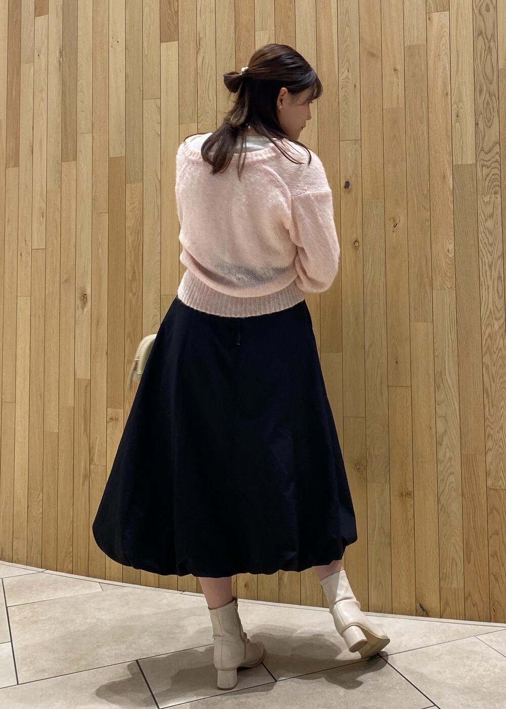 ピンク系のカーディガン/ボレロ、ブラック系のスカート、ベージュ系のボストンバッグを着用したレディースの秋コーディネートの4枚目の写真