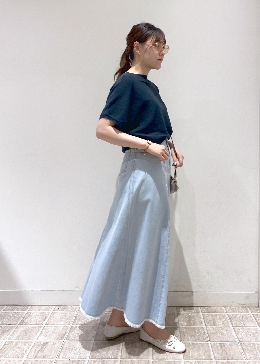 グレー系のショルダーバッグ、ブルー系のデニムスカート、グリーン系のニット/セーターを着用したレディースの夏コーディネートの4枚目の写真