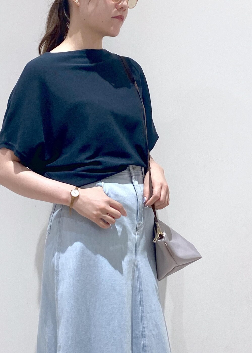 グレー系のショルダーバッグ、ブルー系のデニムスカート、グリーン系のニット/セーターを着用したレディースの夏コーディネートの6枚目の写真