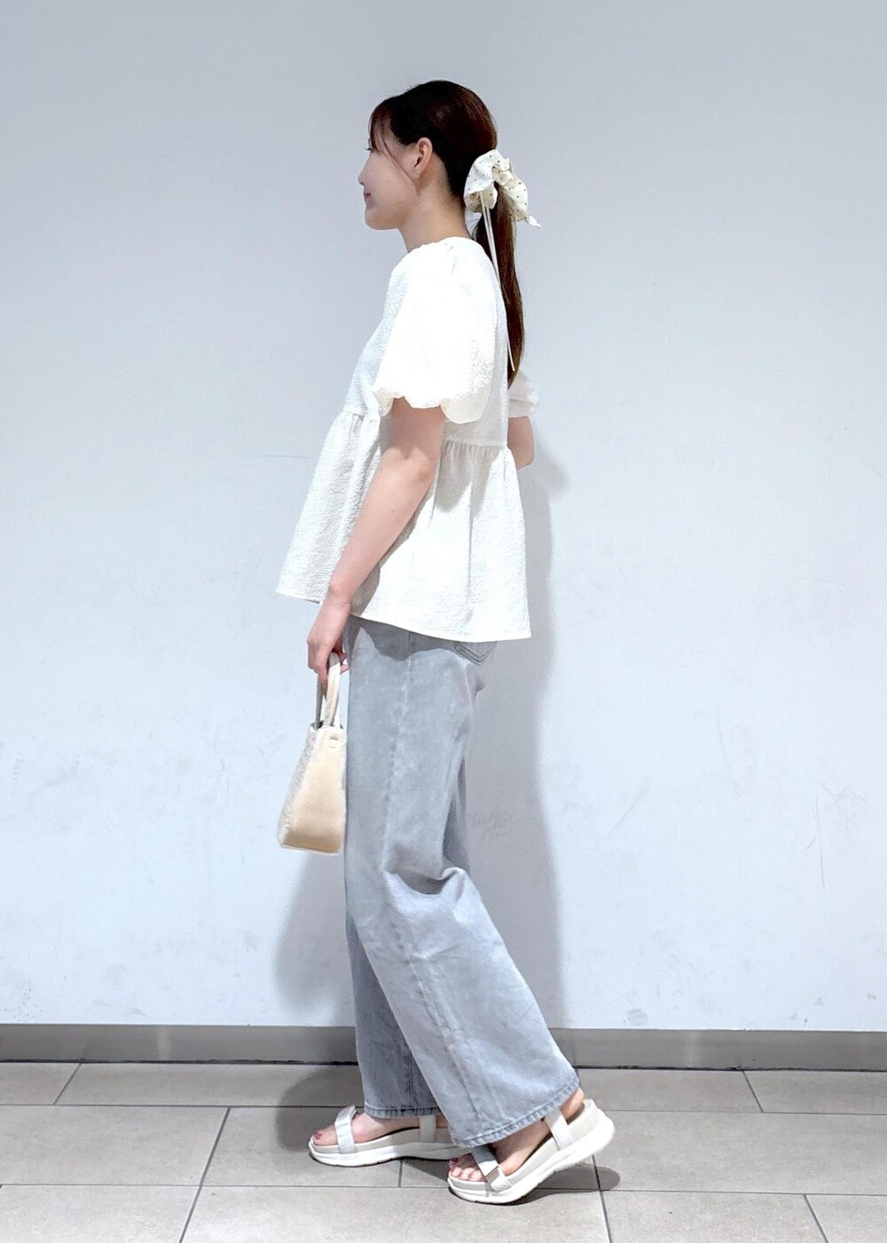 グレー系のデニムパンツ、ホワイト系のサンダル、ホワイト系のシャツ/ブラウスを着用したレディースの夏コーディネートの3枚目の写真