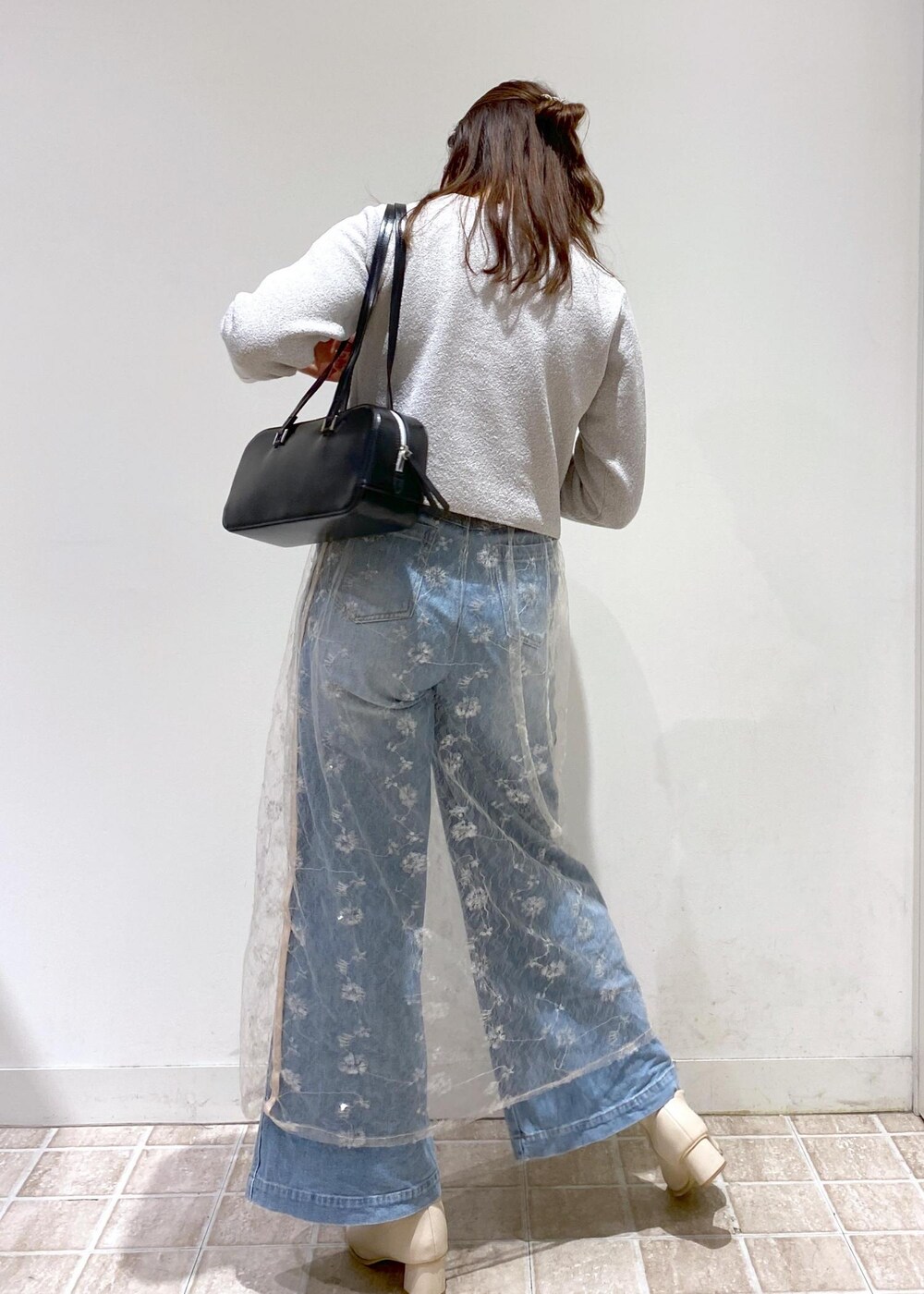 ブルー系のデニムパンツ、グレー系のカーディガン/ボレロ、ホワイト系のスカートを着用したレディースの秋コーディネートの3枚目の写真