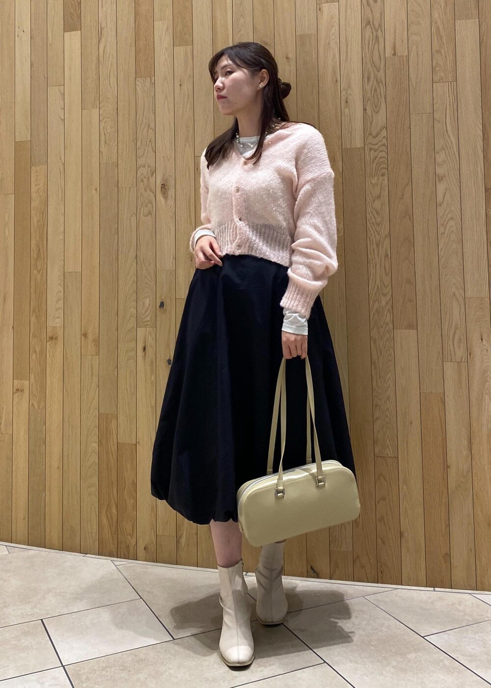 ピンク系のカーディガン/ボレロ、ブラック系のスカート、ベージュ系のボストンバッグを着用したレディースの秋コーディネートの2枚目の写真