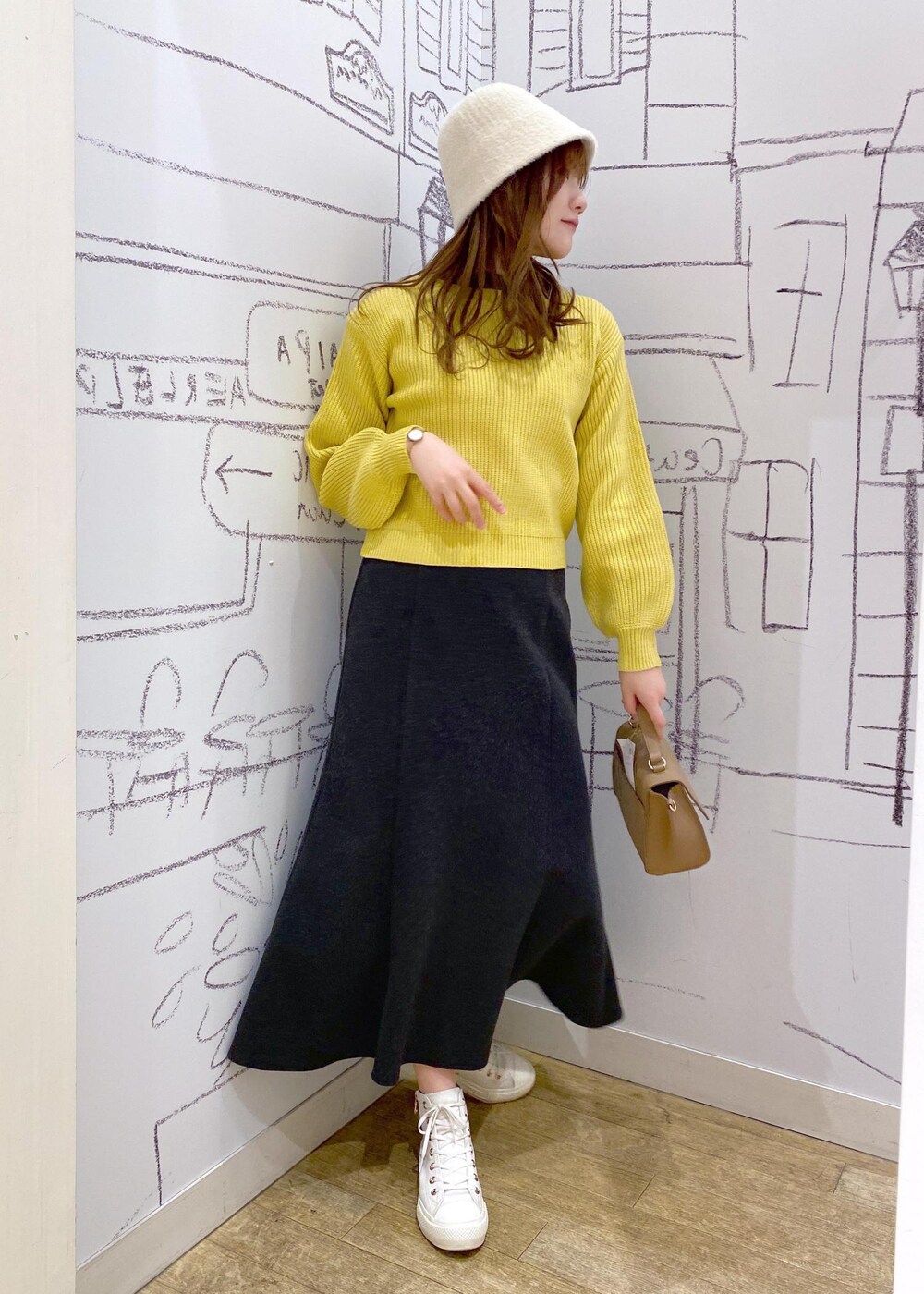 ブラウン系のショルダーバッグ、イエロー系のニット/セーター、ホワイト系のハットを着用したレディースの冬コーディネートの2枚目の写真