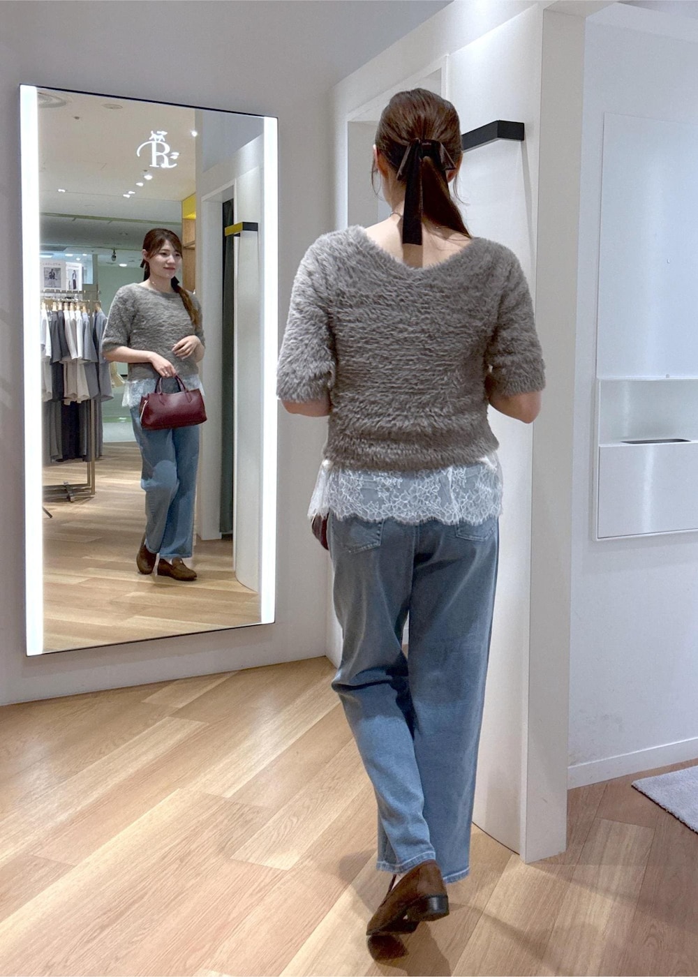 ブルー系のデニムパンツ、ホワイト系のキャミソール、レッド系のトートバッグを着用したレディースの秋コーディネートの3枚目の写真