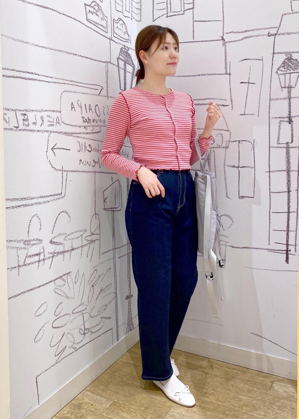 ピンク系のカーディガン/ボレロ、グレー系のバックパック/リュック、ブルー系のデニムパンツを着用したレディースの春コーディネートの2枚目の写真