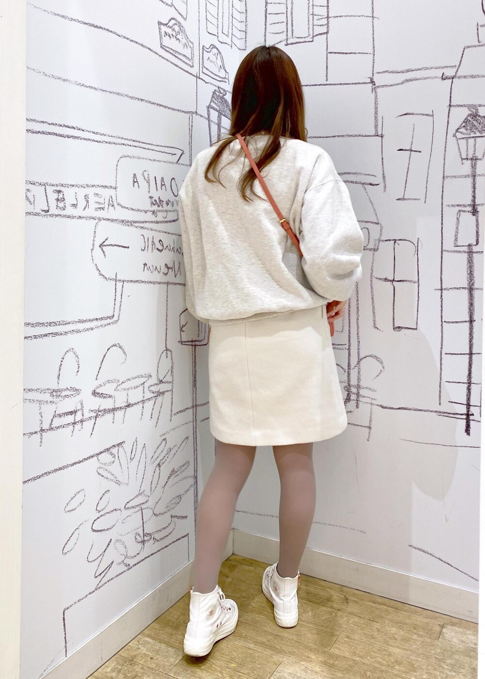 オレンジ系のショルダーバッグ、グレー系のスウェット、ホワイト系のスカートを着用したレディースの冬コーディネートの2枚目の写真