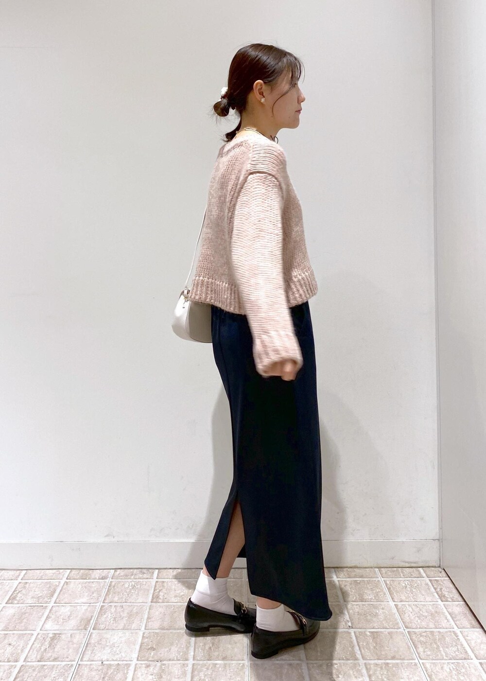 ブラック系のスカート、ベージュ系のムートンコート、ホワイト系のショルダーバッグを着用したレディースの冬コーディネートの5枚目の写真