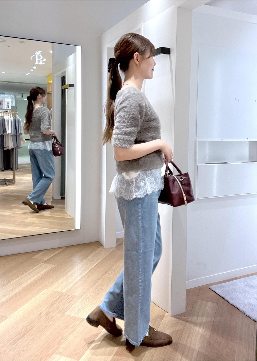 ブルー系のデニムパンツ、ホワイト系のキャミソール、レッド系のトートバッグを着用したレディースの秋コーディネートの4枚目の写真