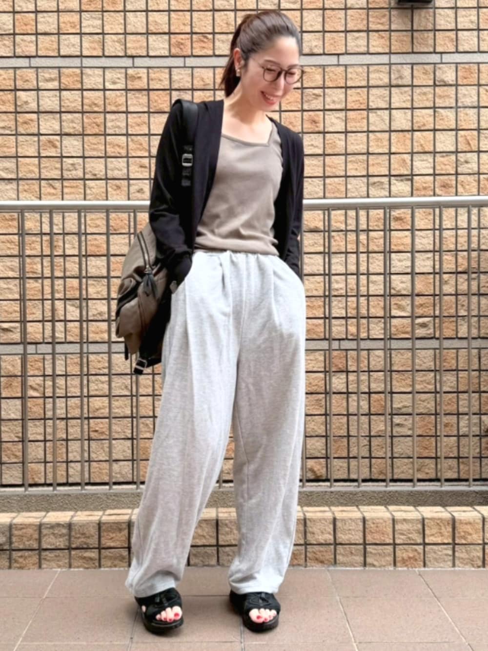 グレー系のパンツ、グリーン系のTシャツ/カットソー、ブラック系のカーディガン/ボレロを着用したレディースの夏コーディネートの2枚目の写真