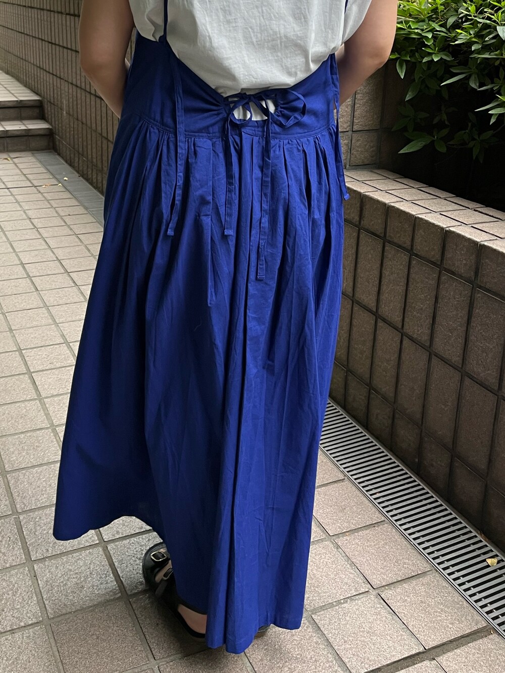ブルー系のワンピース、ゴールド系のかごバッグ、ブラック系のサンダルを着用したレディースの夏コーディネートの5枚目の写真